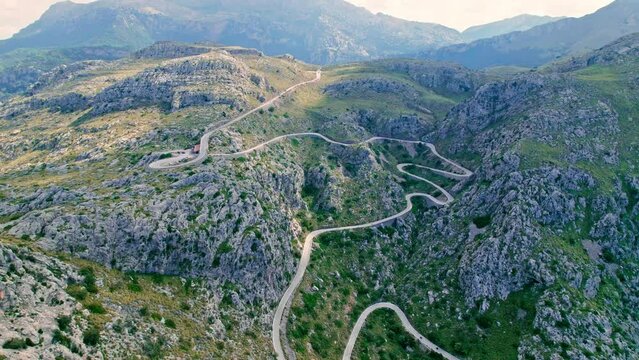 Cars, buses and motorcycles drive on European curved road in Majorca, Spain. Nus de Sa Corbata is a spectacular panoramic snake-like road with curves and rocky landscapes by the Mediterranean.