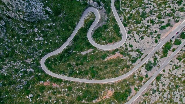 Cars, buses and motorcycles drive on European curved road in Majorca, Spain. Nus de Sa Corbata is a spectacular panoramic snake-like road with curves and rocky landscapes by the Mediterranean.