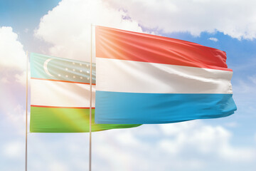 Sunny blue sky and flags of luxembourg and uzbekistan