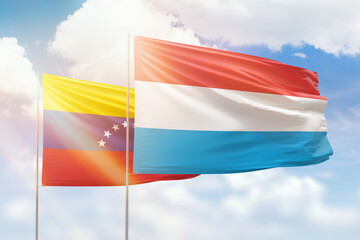 Sunny blue sky and flags of luxembourg and venezuela