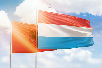 Sunny blue sky and flags of luxembourg and albania