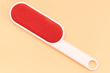 The top view of a red electrostatic clothing brush for removing cat fur lies on a yellow...