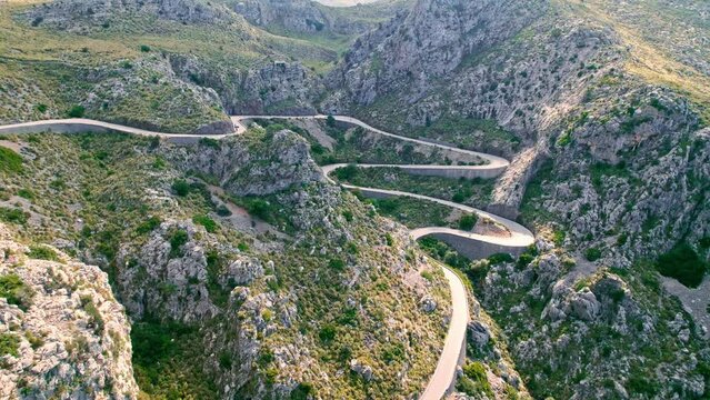 Cars, buses and motorcycles drive on European curved road in Majorca, Spain. Nus de Sa Corbata is a spectacular panoramic snake-like road with curves and rocky landscapes by the Mediterranean.