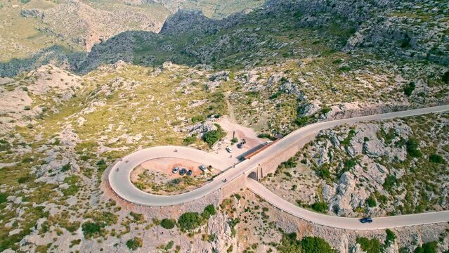 Cars, buses and motorcycles drive on European curved road in Majorca, Spain. Nus de Sa Corbata is a spectacular panoramic snake-like road with curves and rocky landscapes by the Mediterranean.
