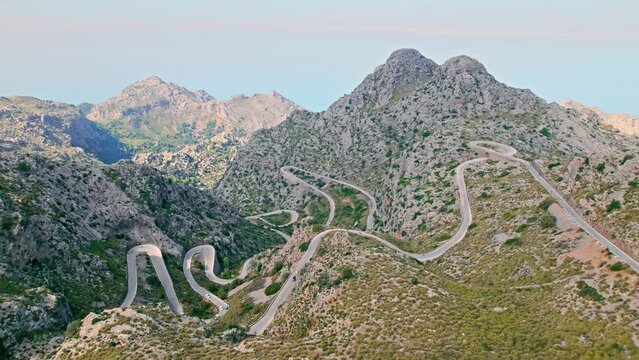 Cars, buses and motorcycles drive on European curved road in Majorca, Spain. Nus de Sa Corbata is a spectacular panoramic snake-like road with curves and rocky landscapes by the Mediterranean.