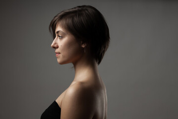 Close up portrait of a beautiful girl. Short hairstyle against gray background.