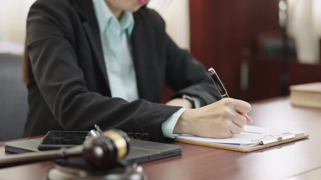 Closeup of female lawye or judge hands taking notes in courtroom,Lawyer business working on table office.