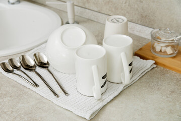 Dry towel and clean dishware on grey countertop near sink in kitchen