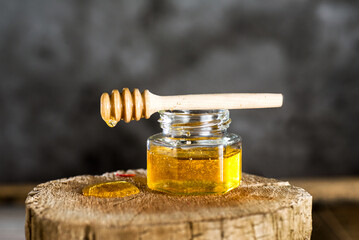 Obraz na płótnie Canvas Fresh transparent honey with dipper on a cut of a tree