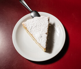 a portion of a ricotta cake on a red table.