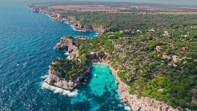 Beautiful cave rocky beach with blue water on a sunny day in Majorca, Spain. Panoramic view from above of a famous tourist attraction Cal&oacute; del Moro Beach by the coast in Mallorca, Balearic Islands.