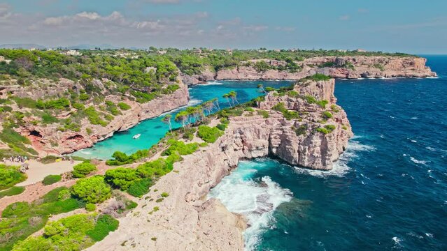 Beautiful cave rocky beach with blue water on a sunny day in Majorca, Spain. Panoramic view from above of a famous tourist attraction Cal&oacute; del Moro Beach by the coast in Mallorca, Balearic Islands.