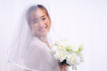 bride in white gown with veil holding flower bouquet