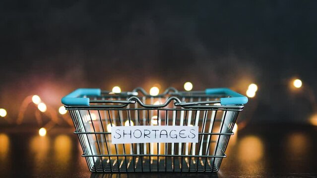 economy after covid, shortages text on empty shopping basket  on dark background with lights