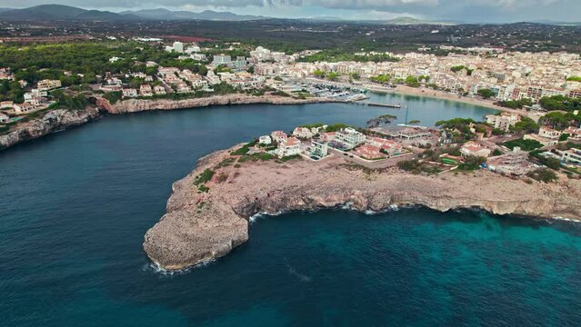 Scenic Porto Cristo Marina view from above with houses by the coast in Majorca. A view of a Spanish village known for amazing Drach Caves on the Balearic Islands, Spain.