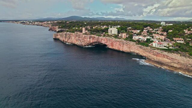 Beautiful view of coastal Porto Cristo village from above on Majorca Island. Torre del Serral dels Falcons by Drach Caves in Balearic Islands, Spain.