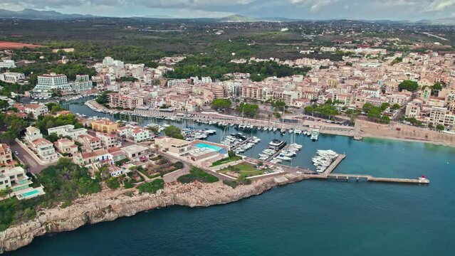 Scenic Porto Cristo Marina view from above with houses by the coast in Majorca. A view of a Spanish village known for amazing Drach Caves on the Balearic Islands, Spain.
