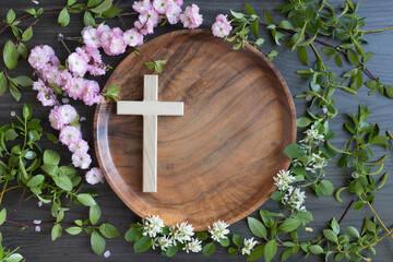 Wood cross on round teak wood tray with frame of fresh branches with pink and white flower blossoms...
