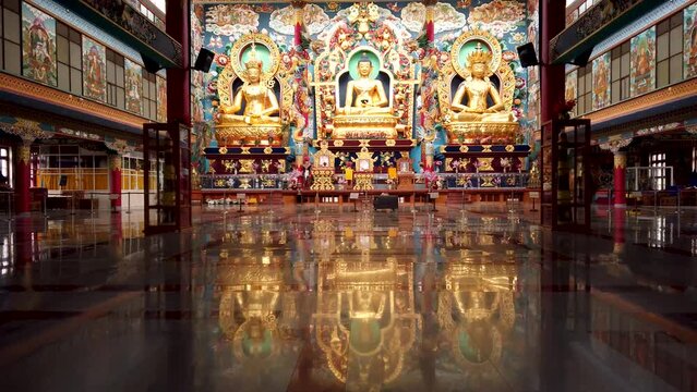  A Dramatic scene of the Tibetan Monastery interiors where large statues of Buddhas in different forms decorated with Gold at Bylakuppe town in India which is an famous travel destination.