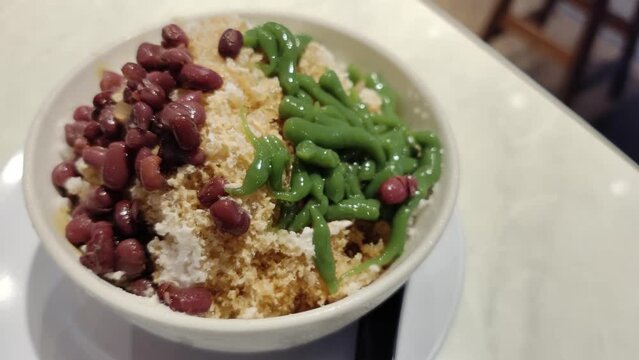 Close-up view of the cendol dessert with gula Melaka syrup. Cendol is made from crushed ice cubes, jelly, coconut milk, and red beans.