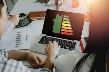 Business team using laptop computer with house icon energy efficiency scale image on office desk, Concept of ecological and bio energetic house. Energy class.