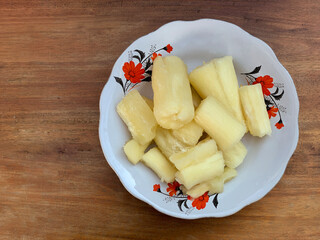 Boiled cassava on a plate with a wooden table background