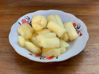 Boiled cassava on a plate with a wooden table background
