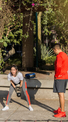 Woman performing exercise routine and her trainer motivating.