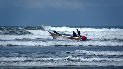Fototapeta na wymiar Fishing boat being launched through the surf, from the beach, in Canoa, Ecuador