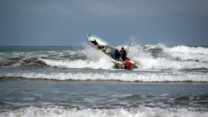 Fishing boat being launched through the surf, from the beach, in Canoa, Ecuador