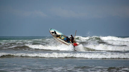 Fishing boat being launched through the surf, from the beach, in Canoa, Ecuador