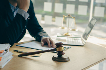 Concepts of justice and lawyers discuss contract paperwork with brass scales on a table with a judge's hammer placed in front of lawyers in the office. Legal, advice, justice, and conceptual services. - obrazy, fototapety, plakaty