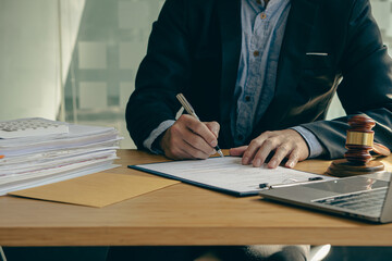 Concepts of justice and lawyers discuss contract paperwork with brass scales on a table with a judge's hammer placed in front of lawyers in the office. Legal, advice, justice, and conceptual services.