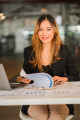 Asian female freelancer working using laptop computer in modern office make an account analysis report real estate investment information Business finance and tax system concept, vertical image.