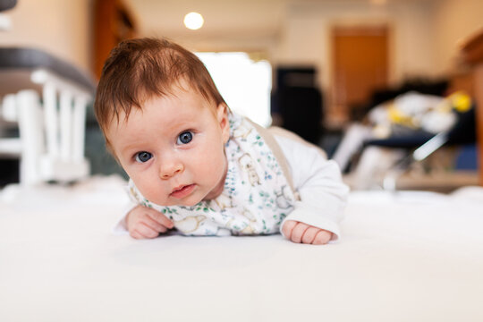 Two month old baby doing tummy time on white mat with copy space