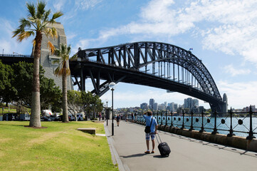 Man with luggage looking at Sydney Harbour Bridge