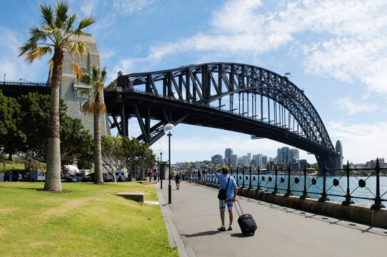 Man with luggage looking at Sydney Harbour Bridge