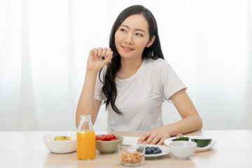 Obraz na płótnie Canvas Diet, Dieting asian young woman write diet plan right nutrition on table with fresh vegetables salad, almond is different food ingredients in green. Nutritionist of healthy, nutrition of weight loss.