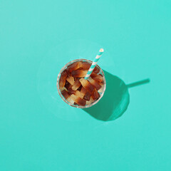 Glass full of gummy candies with a colorful straw on a Tiffany blue-green background. Flat lay. Summer concept