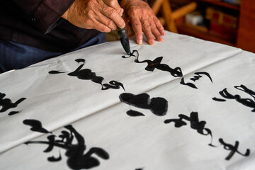 An old calligrapher is writing and creating calligraphy works. Translation: It rains on the pond with light thunder outside Liuwai, and the sound of rain drops and smashes the lotus.