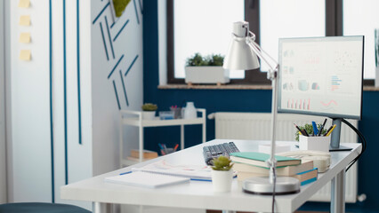 Empty business office with financial statistics on computer, used to plan company development with sales charts and data graphs. No people working in professional startup workplace.