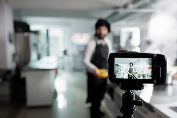 Close up of camera recording head chef cooking delicious fine dining dish in restaurant kitchen for...