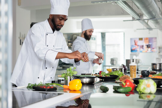 Gastronomy expert wearing cooking uniform while preparing delicious gourmet dish for dinner service at restaurant. Head chef having pan on gas cooker while cooking tasty food meal in kitchen.