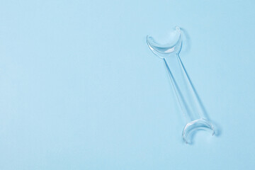 Retractor Dental lip retractor Access to the oral cavity. Wide mouth opening for a dental procedure on a clean blue background
