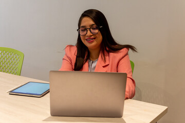 Portrait of young white woman in a busy modern workplace working and  holding phone or tablet in a cowering space