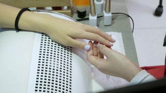 woman's hand while gel nail polish in nail salon. beauty spa hand therapy