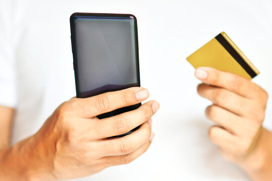Hombre sosteniendo su telefono y tarjeta de credito para hacer una compra en linea.