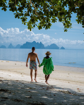 couple of men and woman on the beach of the tropical Island Naka Island near Phuket Thailand, woman at a swing on the beach, and man walking on a tropical beach