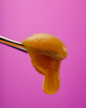 Live Resin Sauce sitting on a titanium dab tool with a pink background. 