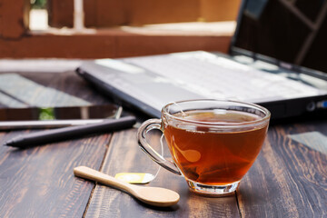 Close-up of a cup of hot tea or coffee placed on a desk with a computer. Or at a table for coffee by the window at work or home, at sunset or in the morning.